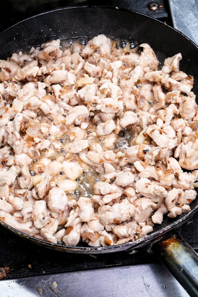 Cooking chicken pieces in skillet for empanadas