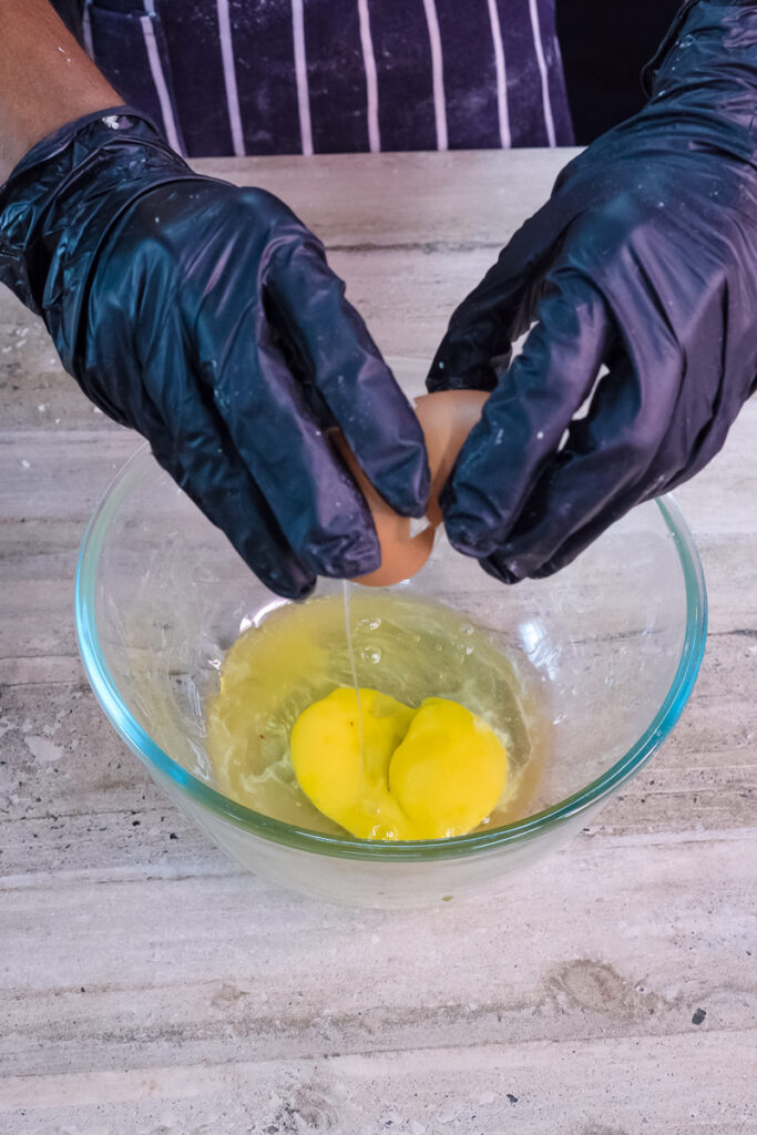 Cracking fresh eggs into bowl for pancake roll batter