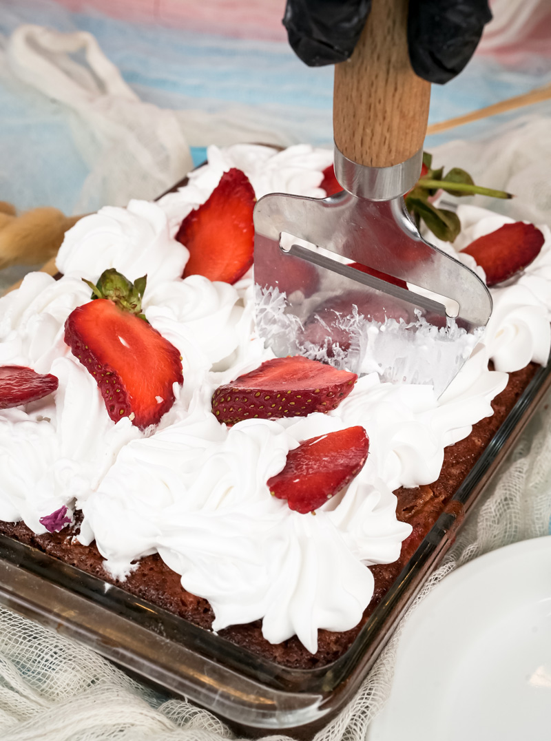 Cutting strawberry earthquake cake with ice cream scoop