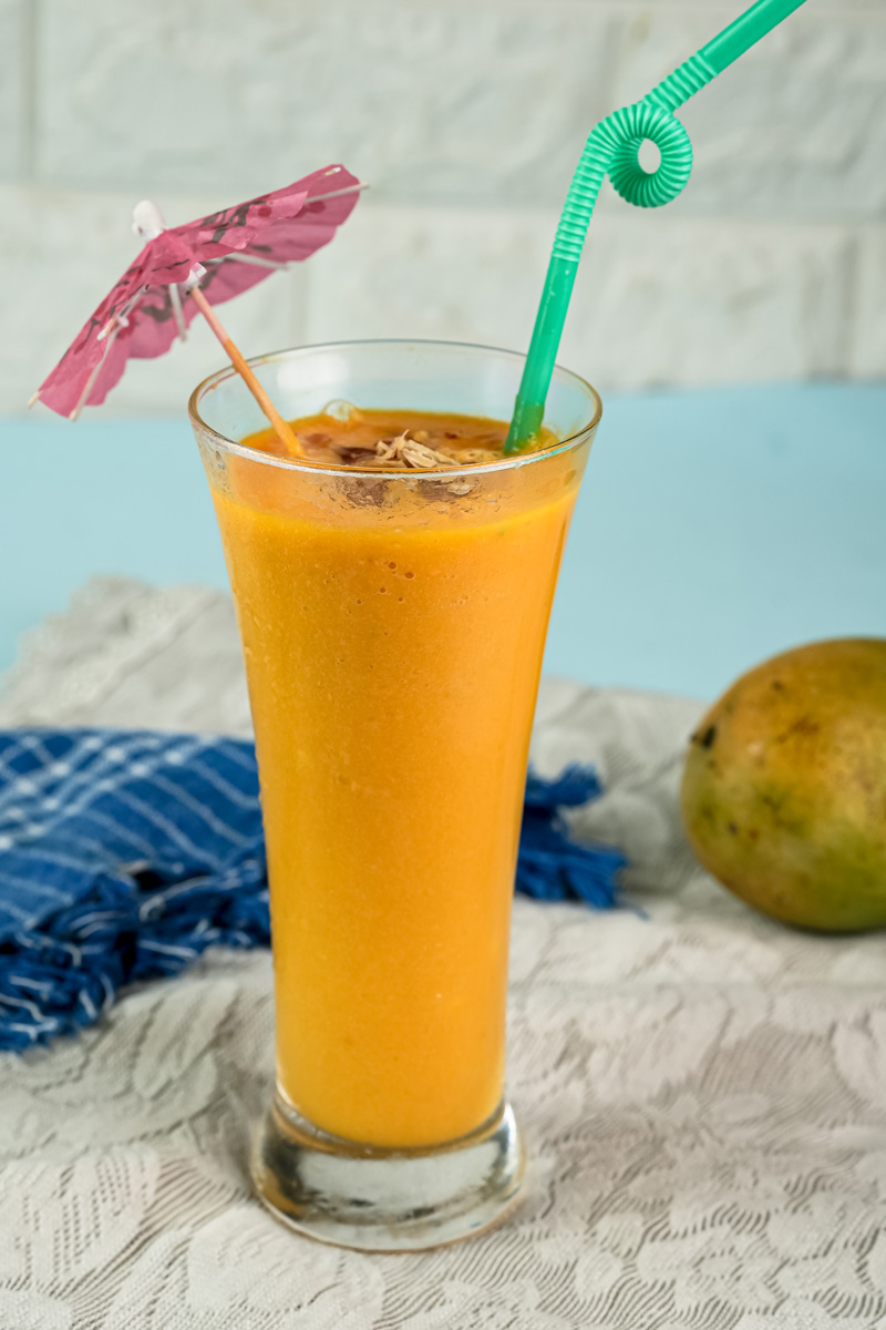 Decorated mango milkshake on white wooden background