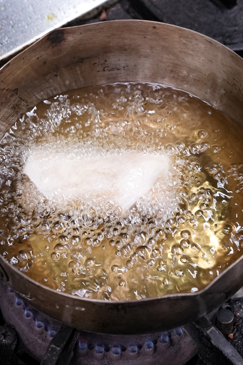 Deep frying banana lumpia in hot oil