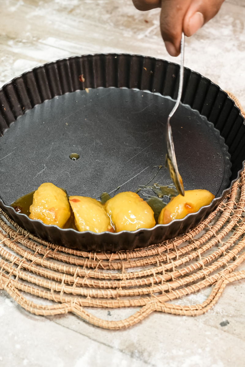 Drizzling caramel sauce over apple slices in tart pan for Tarte Tatin