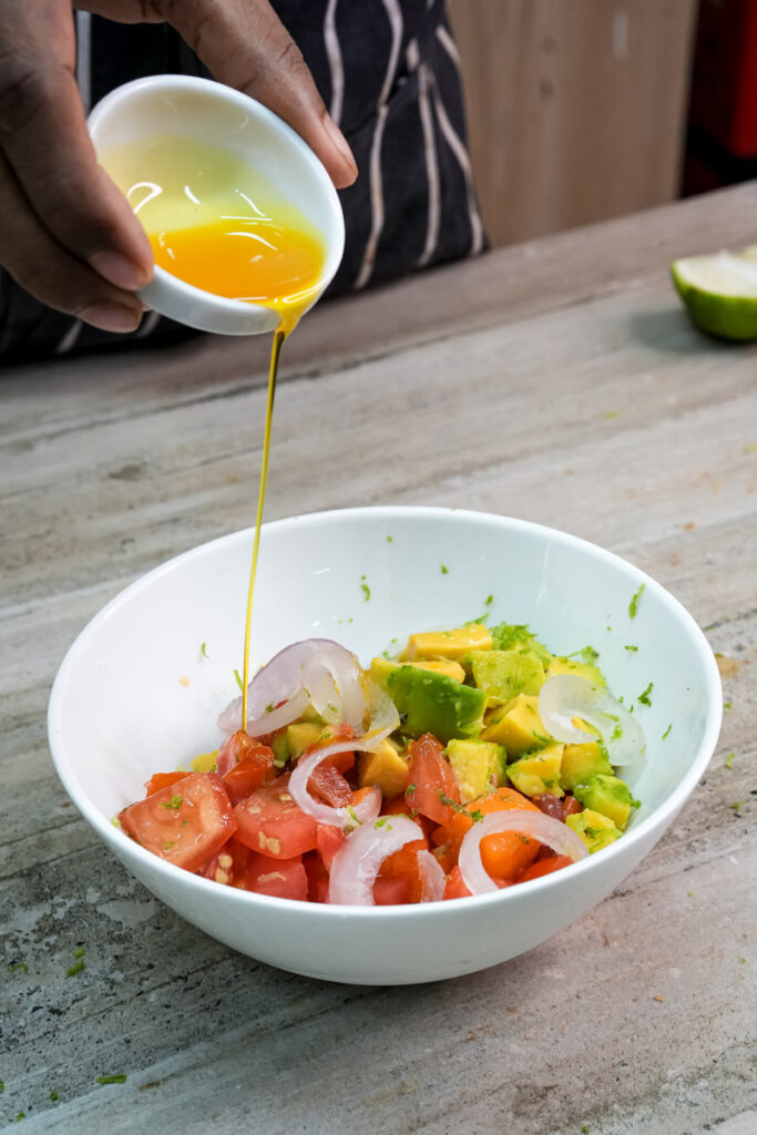 Drizzling olive oil over fresh mango avocado salad