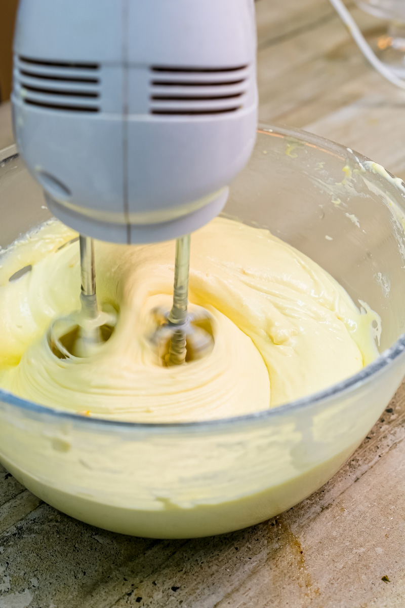 Electric mixer beating citrus cake batter ingredients