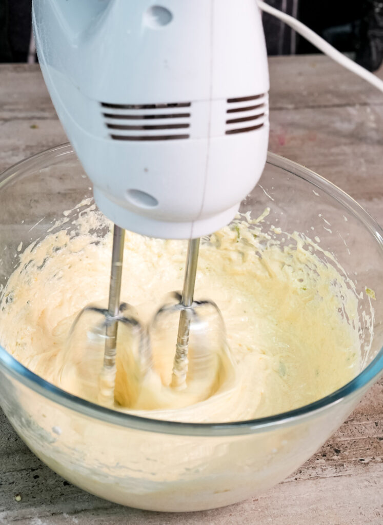 Electric mixer whipping Madeira cake batter in glass bowl