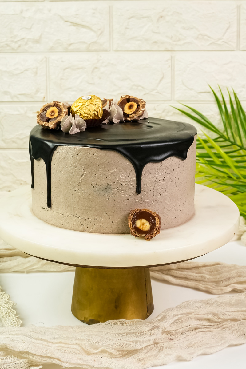 Ferrero Rocher cake on gold cake stand with chocolate drip glaze