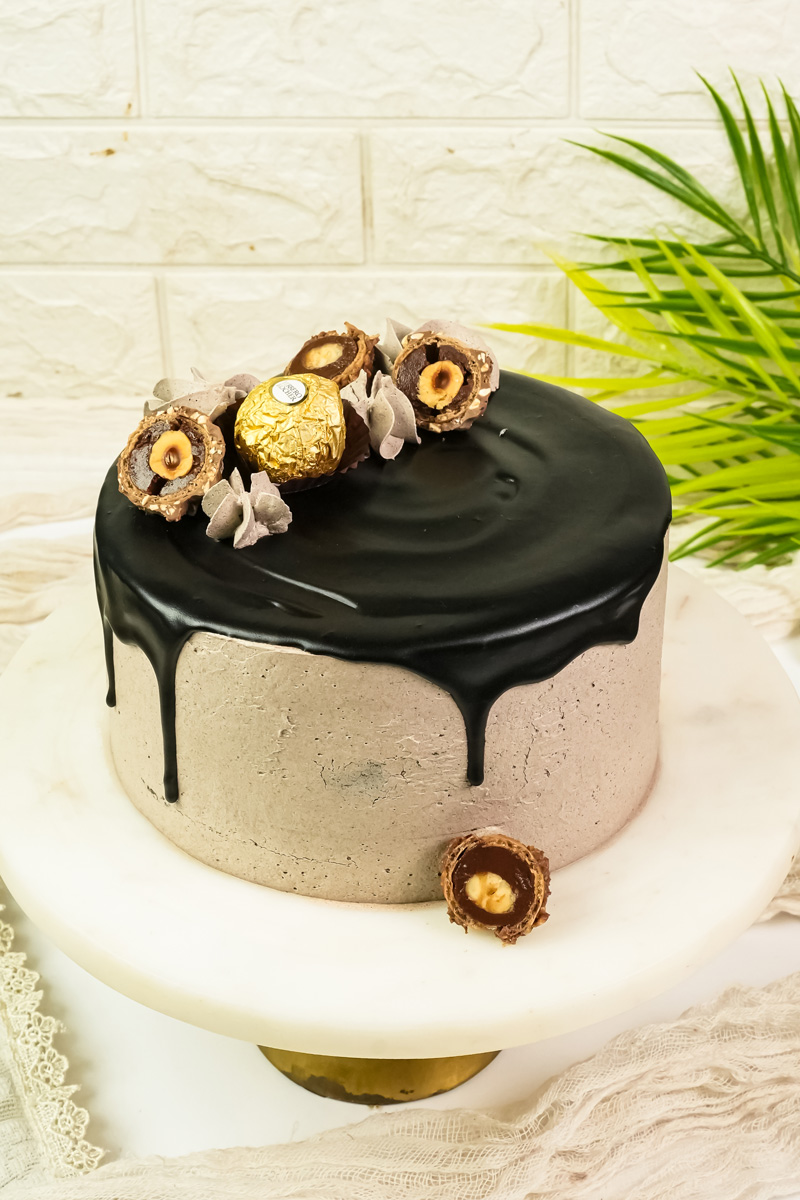 Ferrero Rocher cake on white cake stand with palm leaf decoration