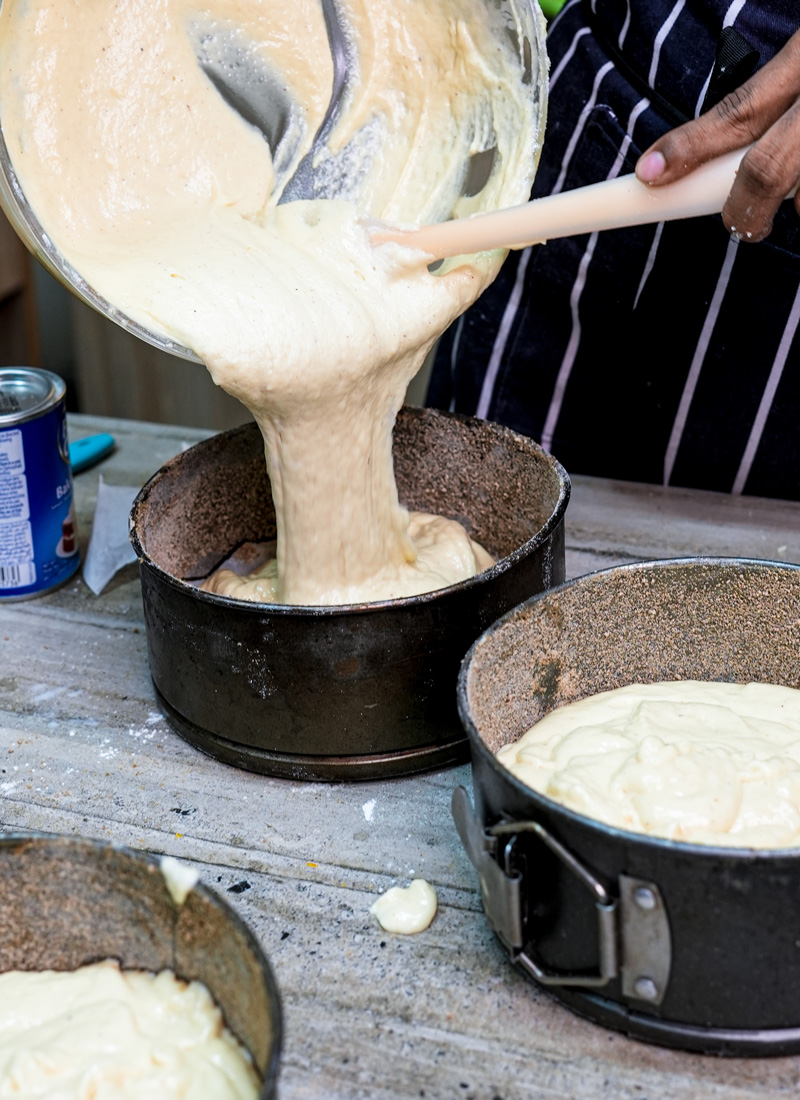 Filling multiple cake pans with churro cake batter for baking