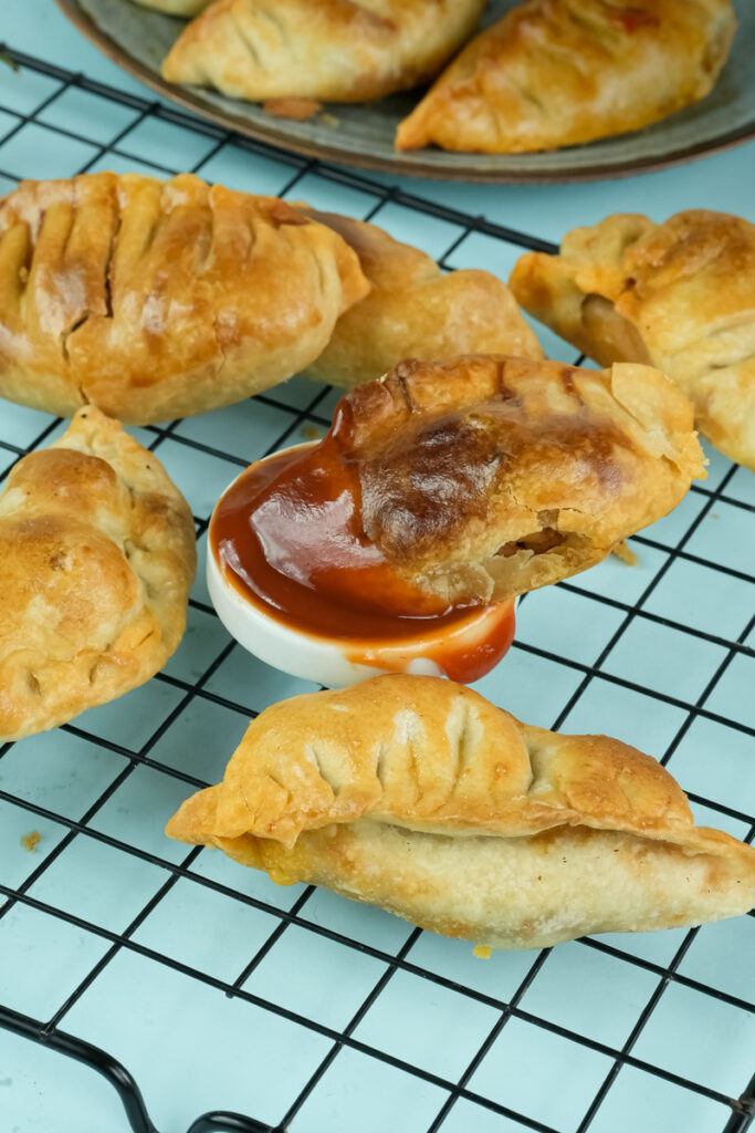 Finished chicken empanadas cooling on wire rack