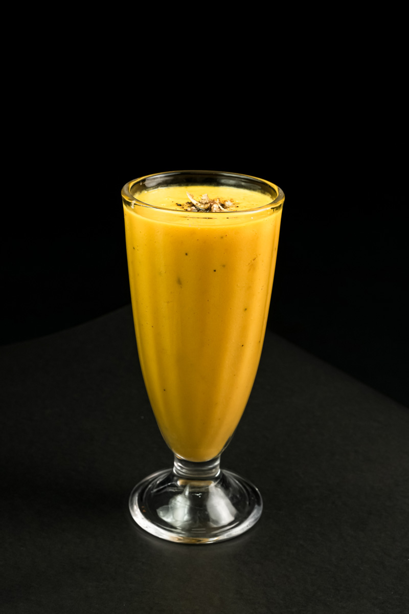 Finished mango lassi drink with cardamom garnish