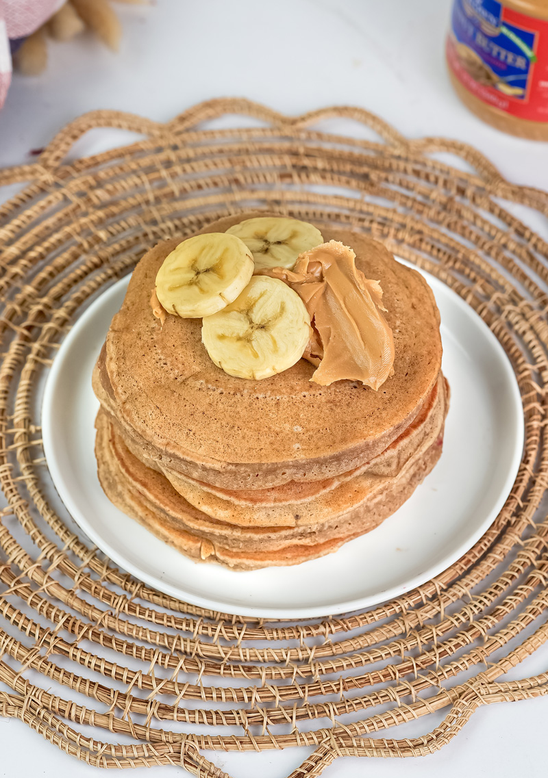 Fluffy peanut butter pancake stack with banana and nut toppings
