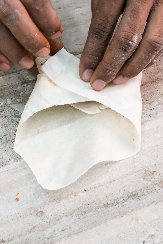Folding lumpia wrapper around banana filling