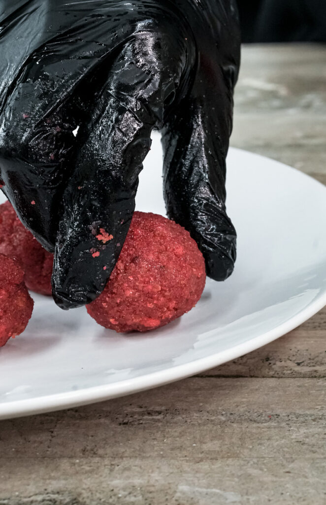 Formed red strawberry cake balls on white plate ready for dipping