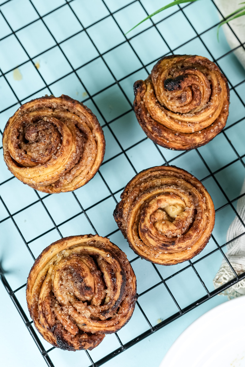 Four golden cruffins arranged on black cooling rack