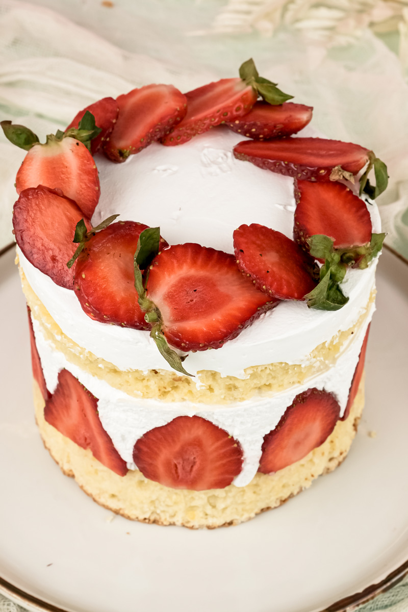 Fraisier cake topped with sliced strawberries and mint leaves