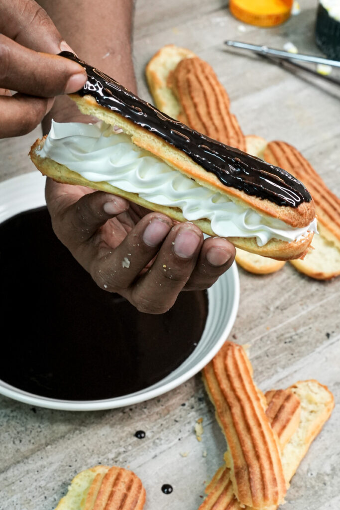 Fresh eclair with whipped cream filling and chocolate topping ready to serve