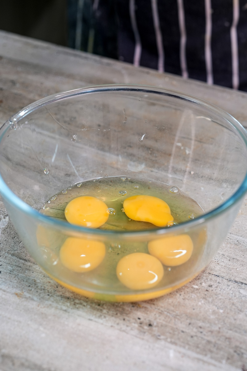 Fresh eggs cracked into glass bowl for opera cake batter