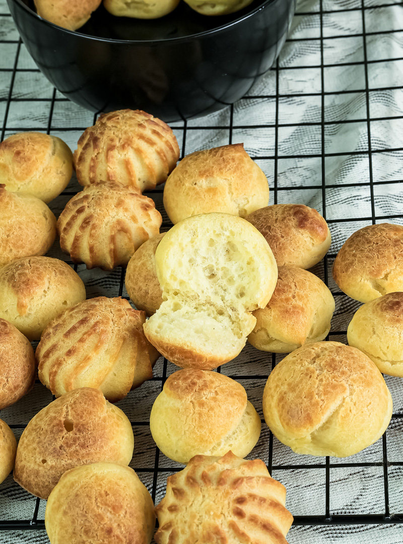 Freshly baked choux pastry cooling with cross-section showing airy texture