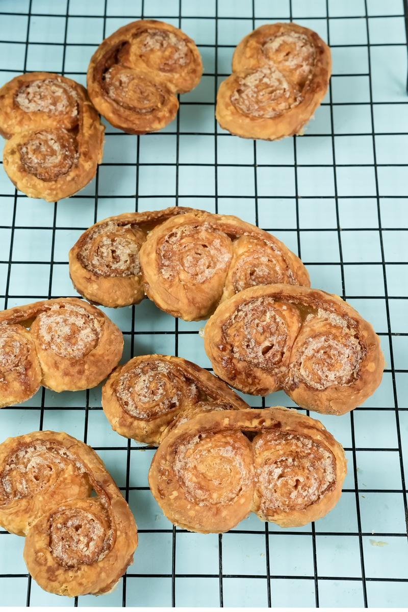 Freshly baked palmiers with flaky layers on cooling rack