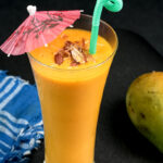 Garnished mango milkshake with umbrella and nuts