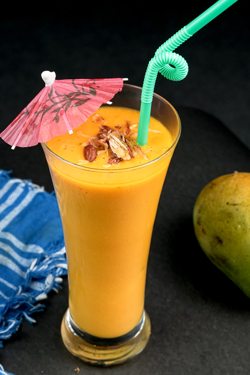 Garnished mango milkshake with umbrella and nuts