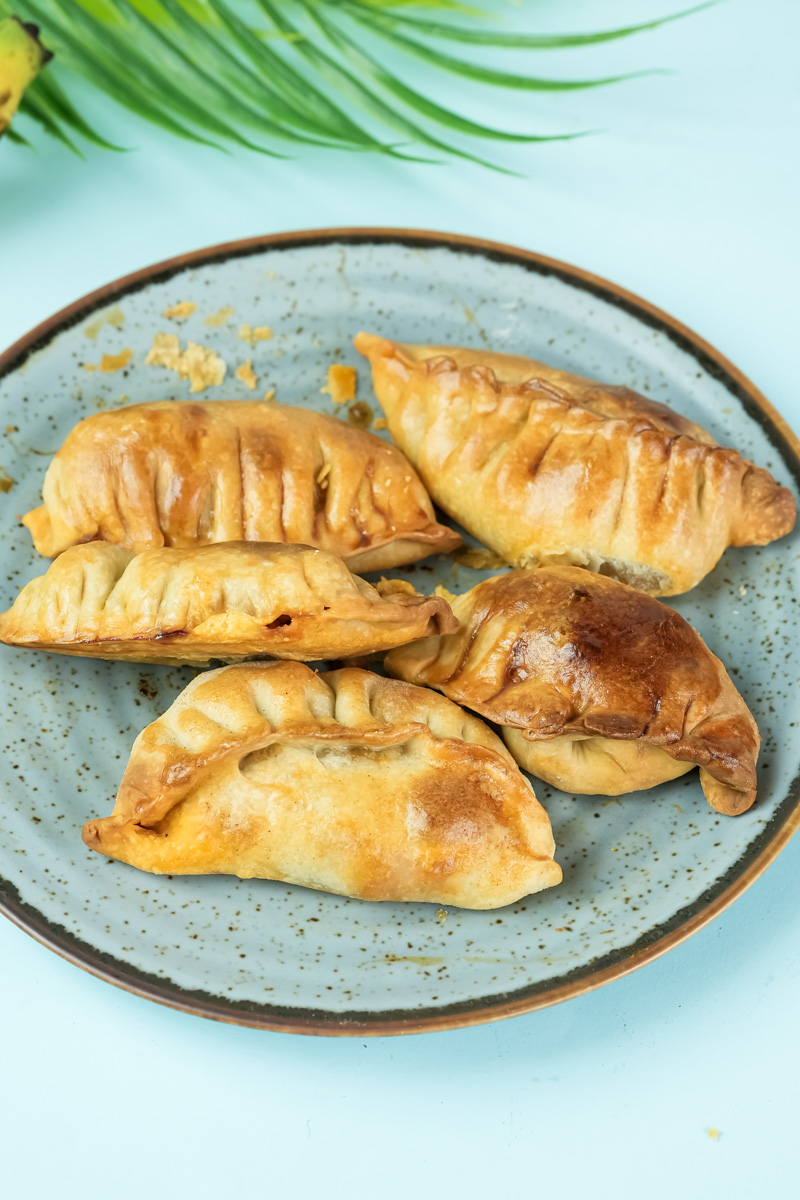 Golden-brown baked chicken empanadas on ceramic plate