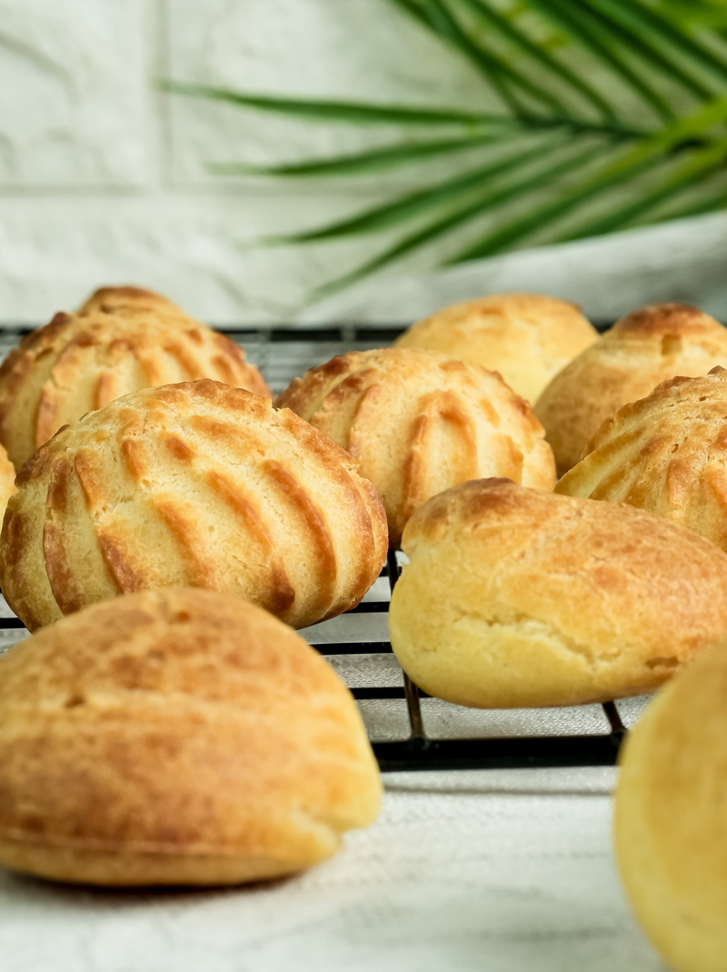 Golden brown choux pastry puffs on cooling rack