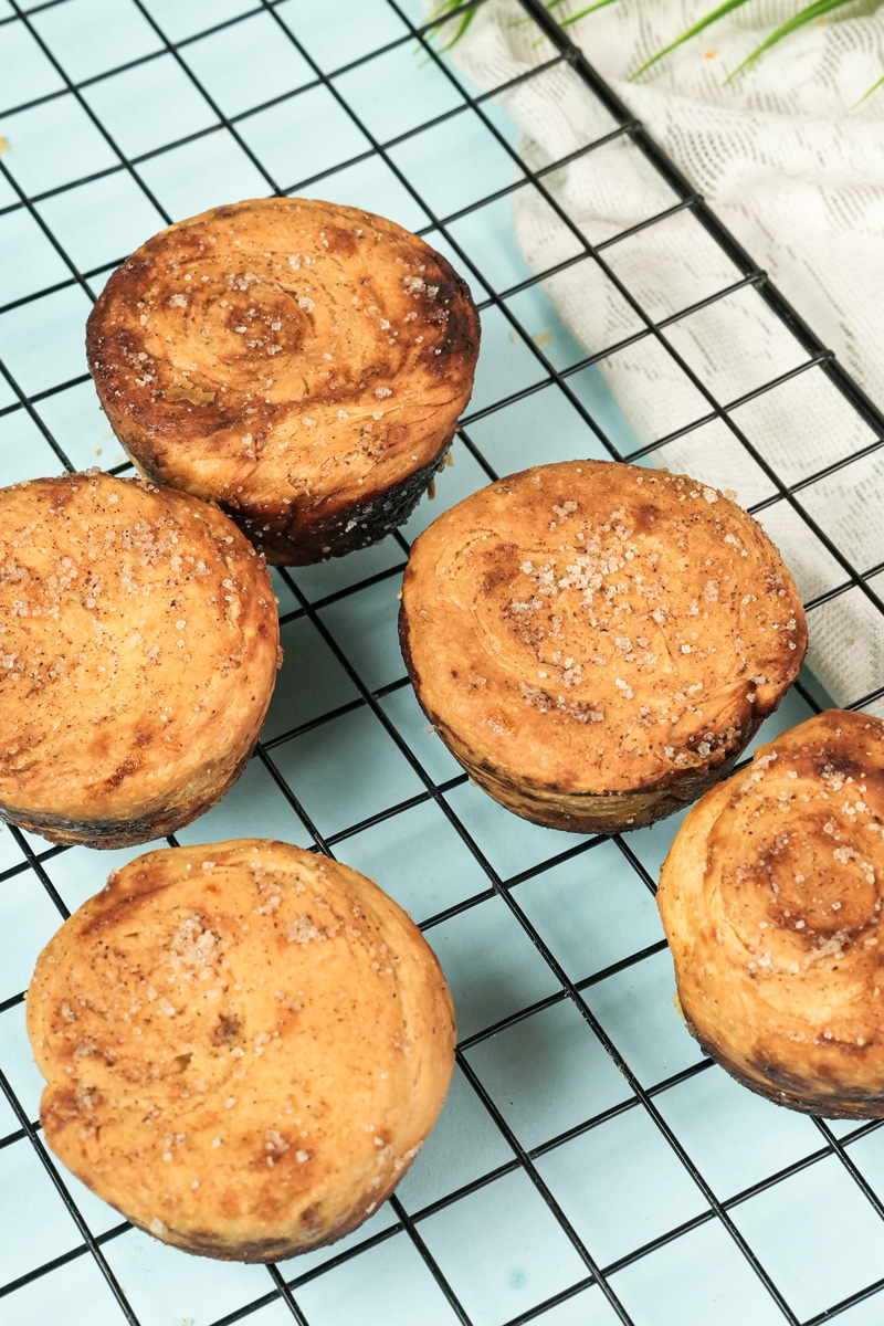 Golden brown kouign amann pastries cooling on wire rack