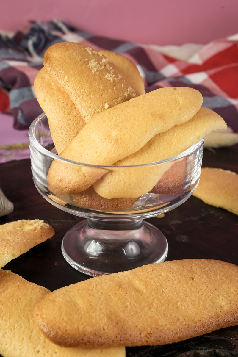 Golden ladyfinger cookies arranged in glass serving bowl
