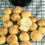 Homemade choux pastry on wire rack with halved piece displaying interior
