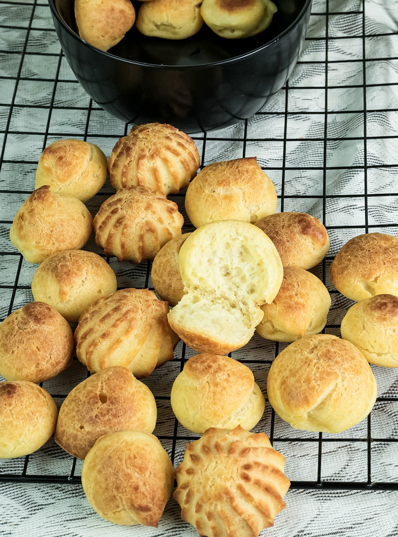 Homemade choux pastry on wire rack with halved piece displaying interior