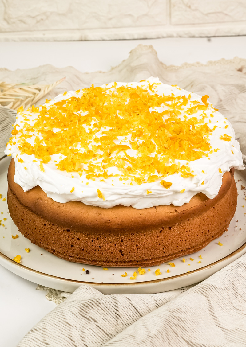 Homemade citrus cake with white frosting and fresh citrus zest topping
