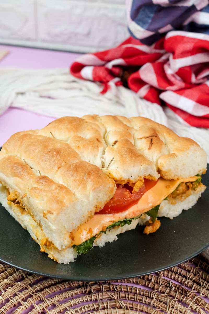 Homemade focaccia sandwich with layered fillings on dark plate