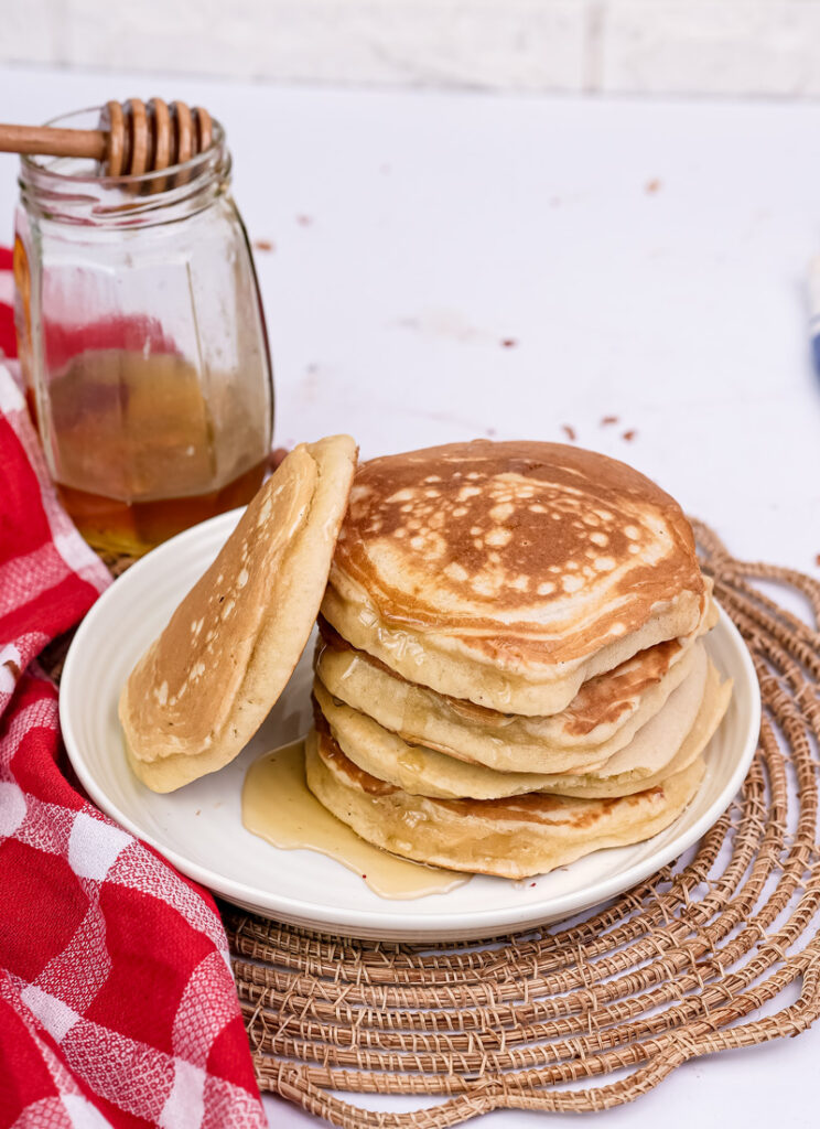 Homemade gluten free pancakes with honey and red checkered kitchen towel