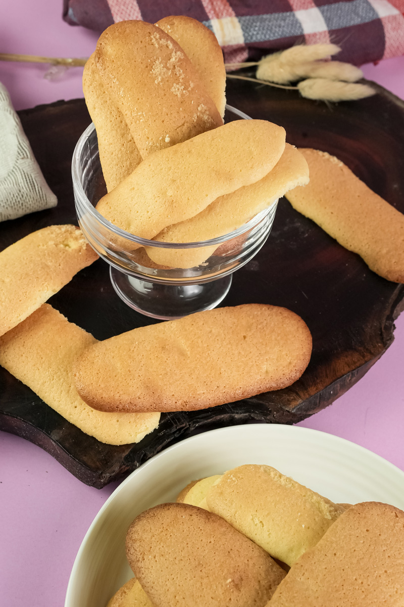 Homemade ladyfinger cookies in glass bowl and on plate