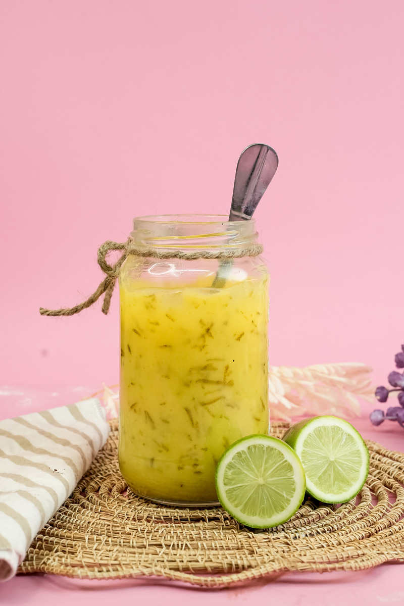 Homemade lemon curd in glass jar with fresh limes