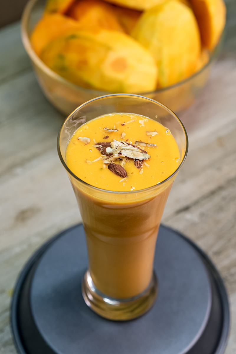 Homemade mango milkshake with almond garnish in glass