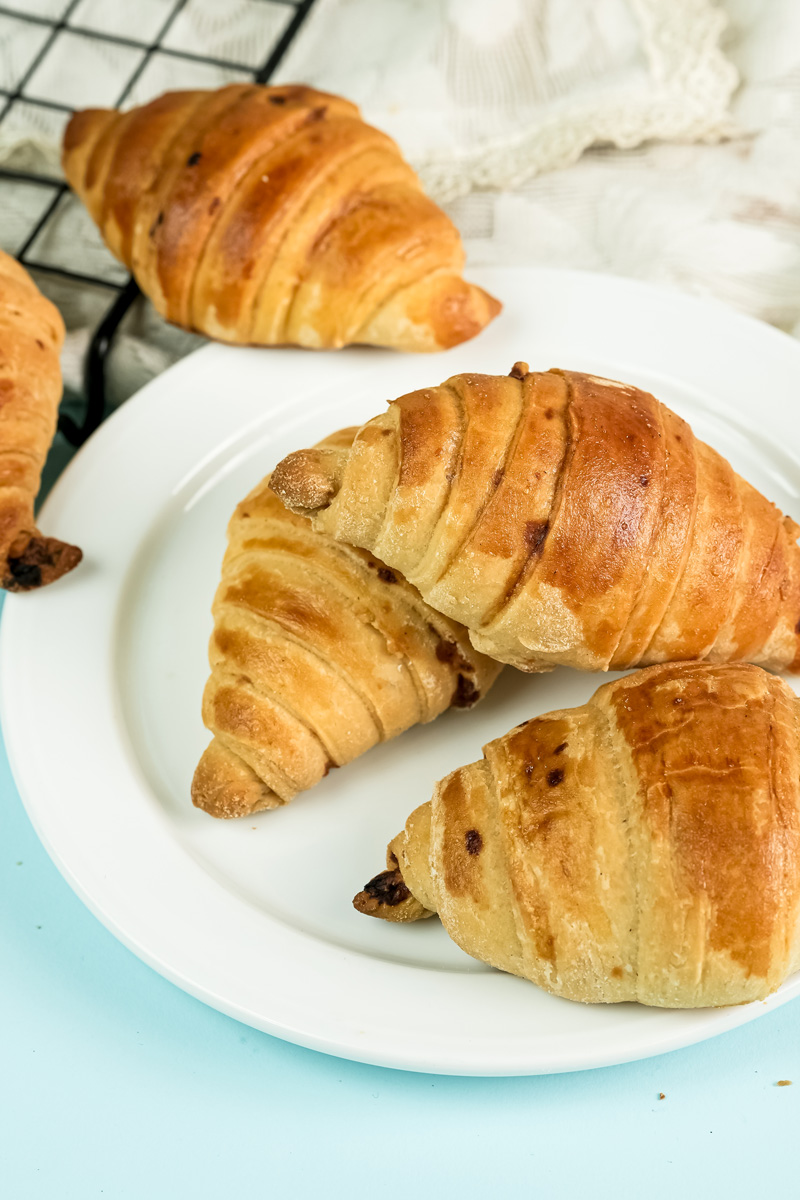 Homemade raisin croissants cooling on plate and wire rack