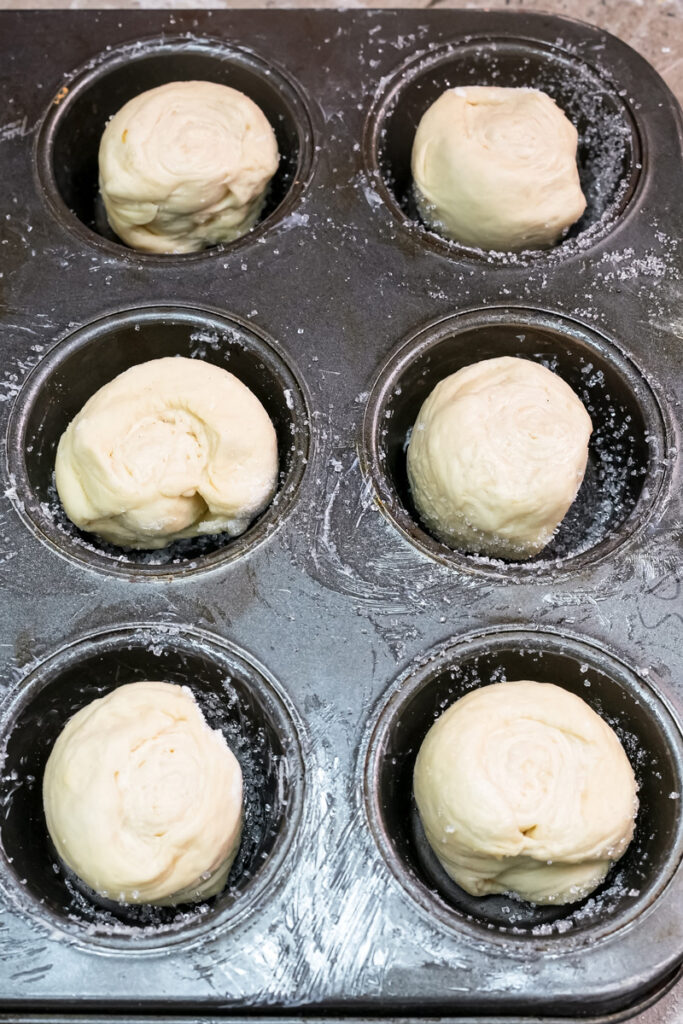 Kouign amann dough pieces in muffin tin