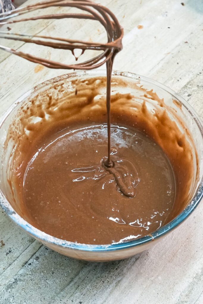 Lifting whisk showing chocolate cake batter consistency