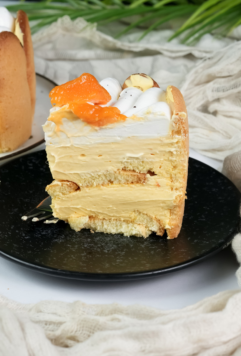 Mango charlotte cake slice revealing layered ladyfinger and cream structure