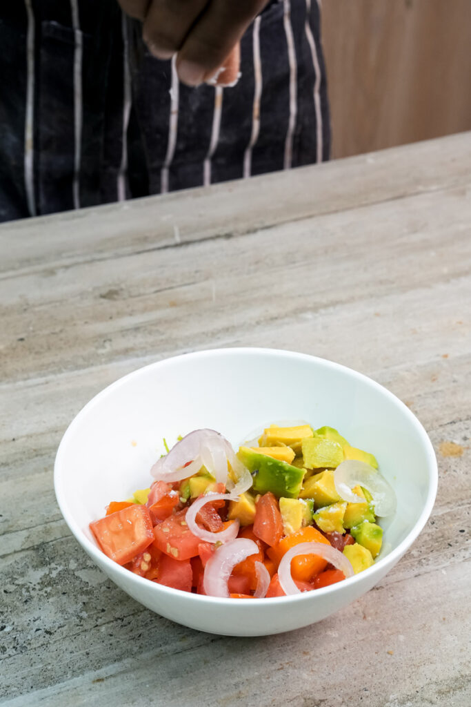 Mixed diced avocado, mango, tomato and onion in white bowl