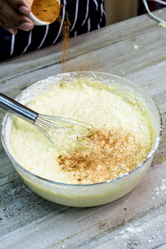 Mixing cinnamon into churro cake batter with wire whisk