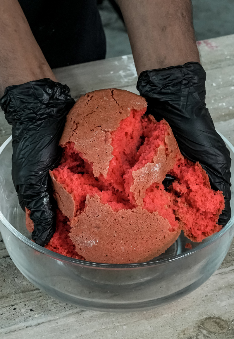 Mixing red strawberry cake crumbs in glass bowl for cake pops