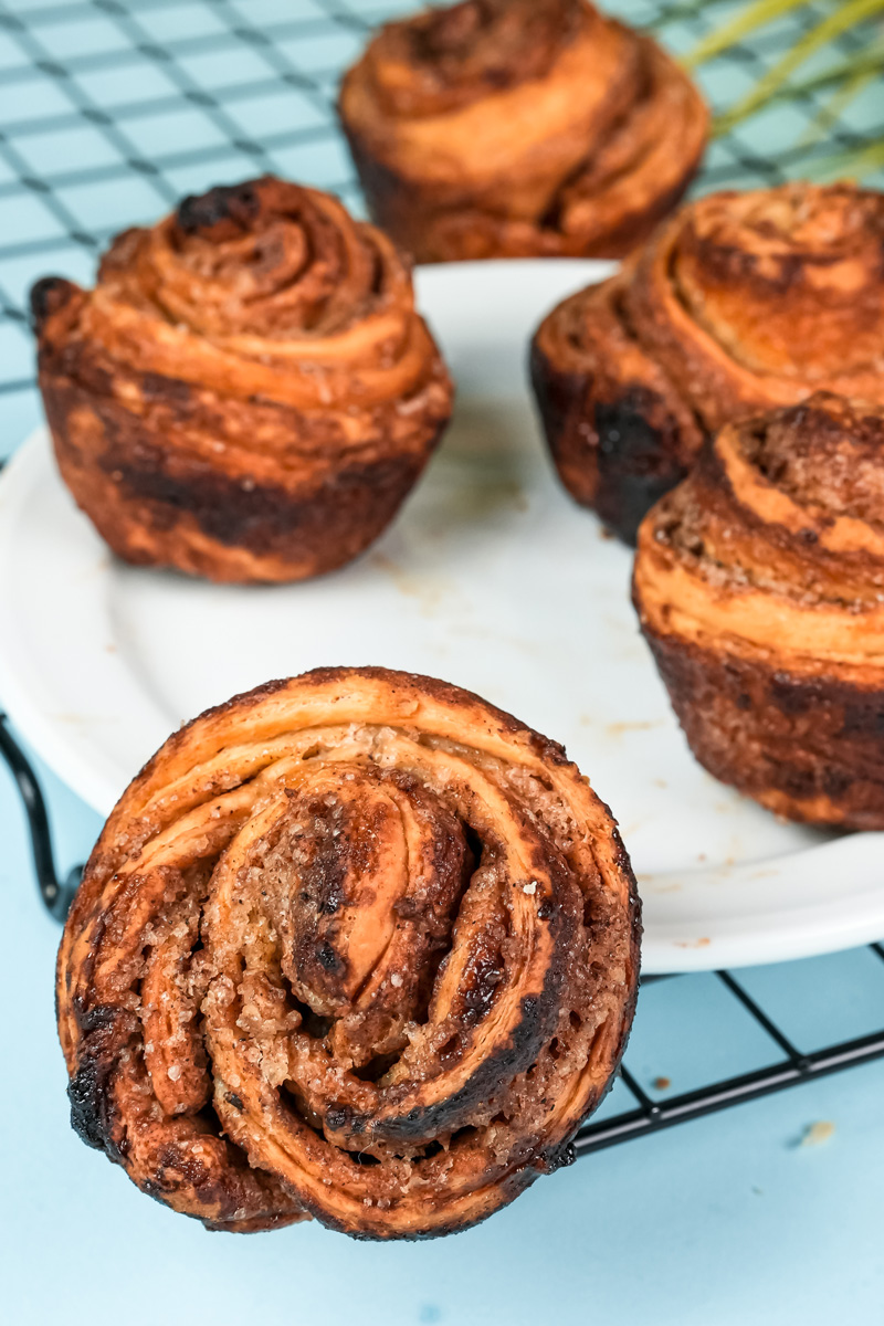 Multiple homemade cruffins displayed on cooling rack and white plate