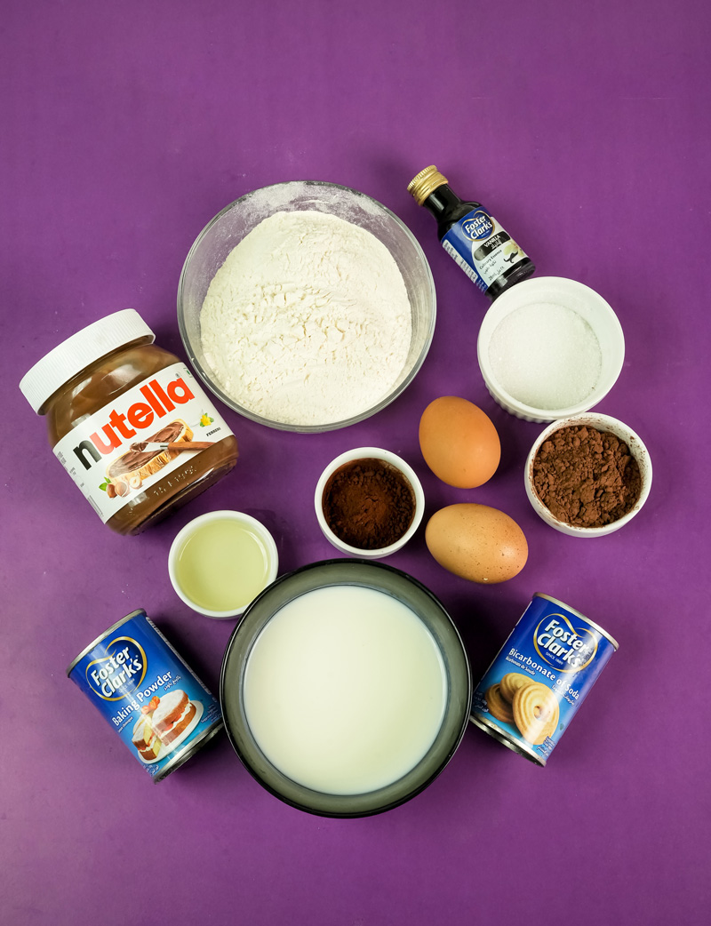 Nutella pancake ingredients laid out - flour, eggs, milk, Nutella, cocoa powder, baking powder
