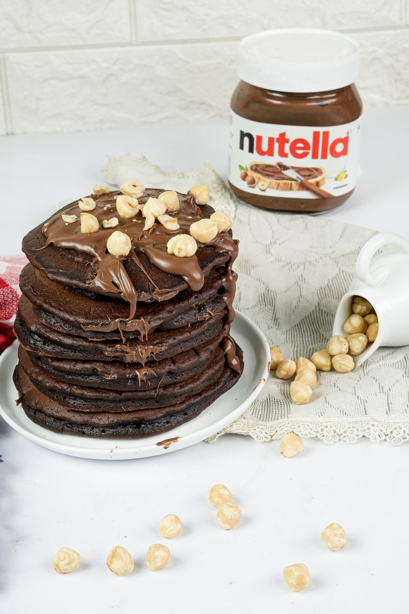 Nutella pancake tower with chocolate drizzle and hazelnuts
