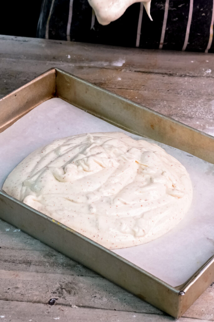 Opera cake batter poured into lined rectangular baking pan