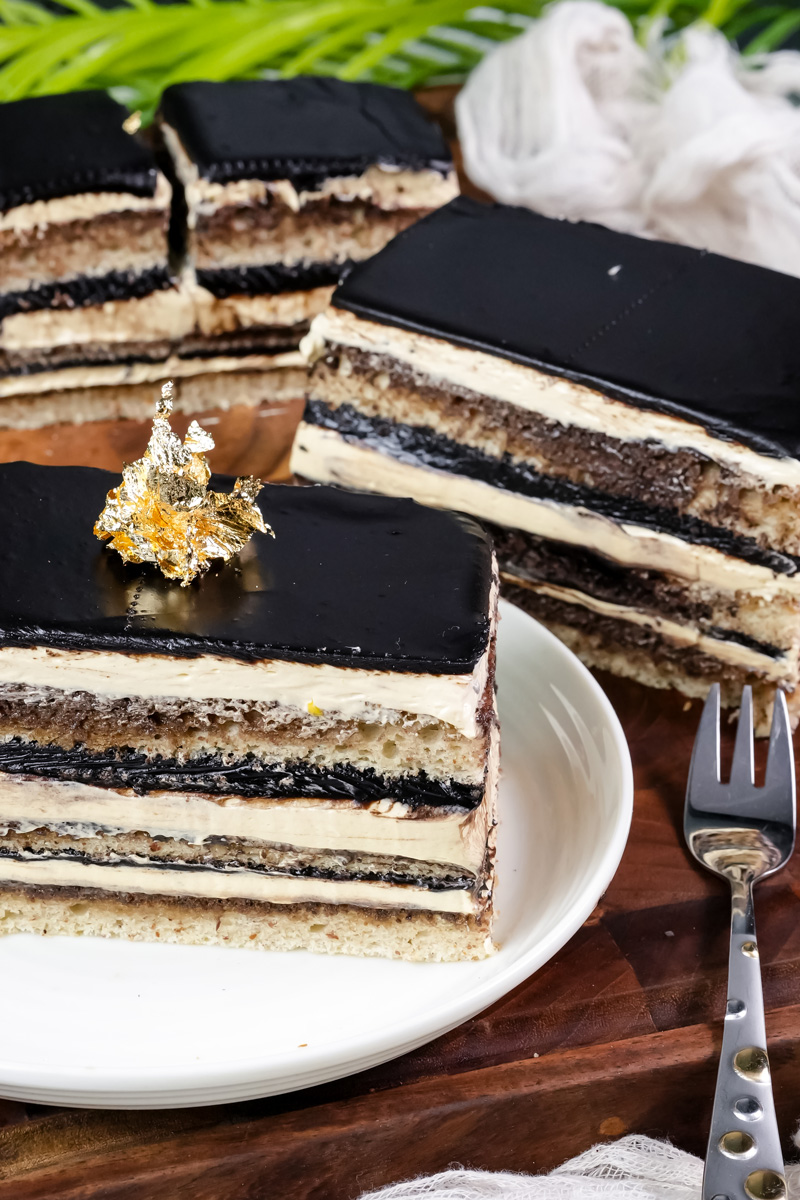 Opera cake slice with gold leaf garnish showing distinct layers and chocolate glaze