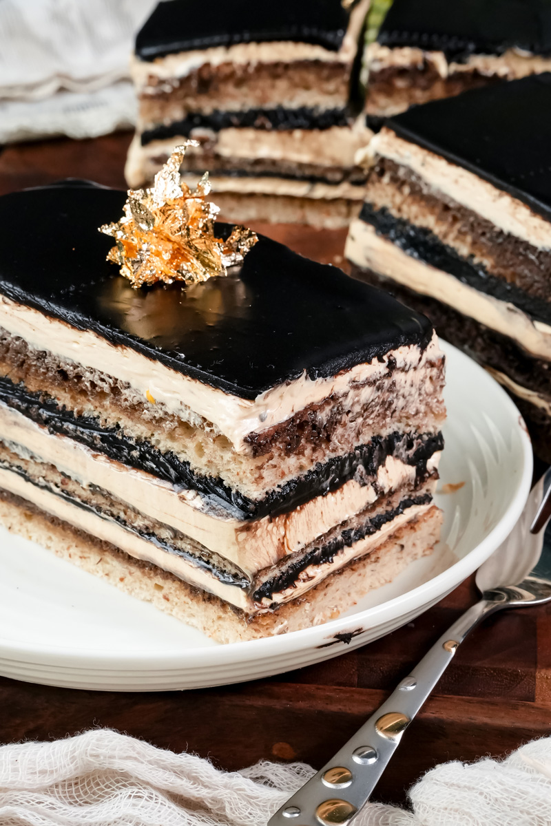 Opera cake slice with mirror chocolate glaze and gold leaf topping